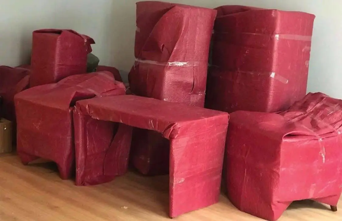 Tuzla nakliyat: kırmızı koruyucuyla paketlenmiş masa ve koltuklar